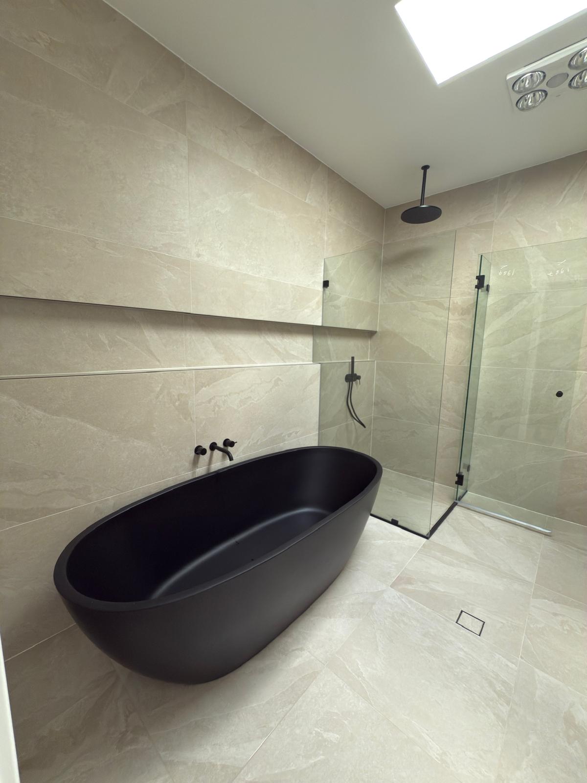 Black freestanding bath under skylight — plumbing work completed in Gerringong by Shellharbour Plumbing (licensed Illawarra plumber)