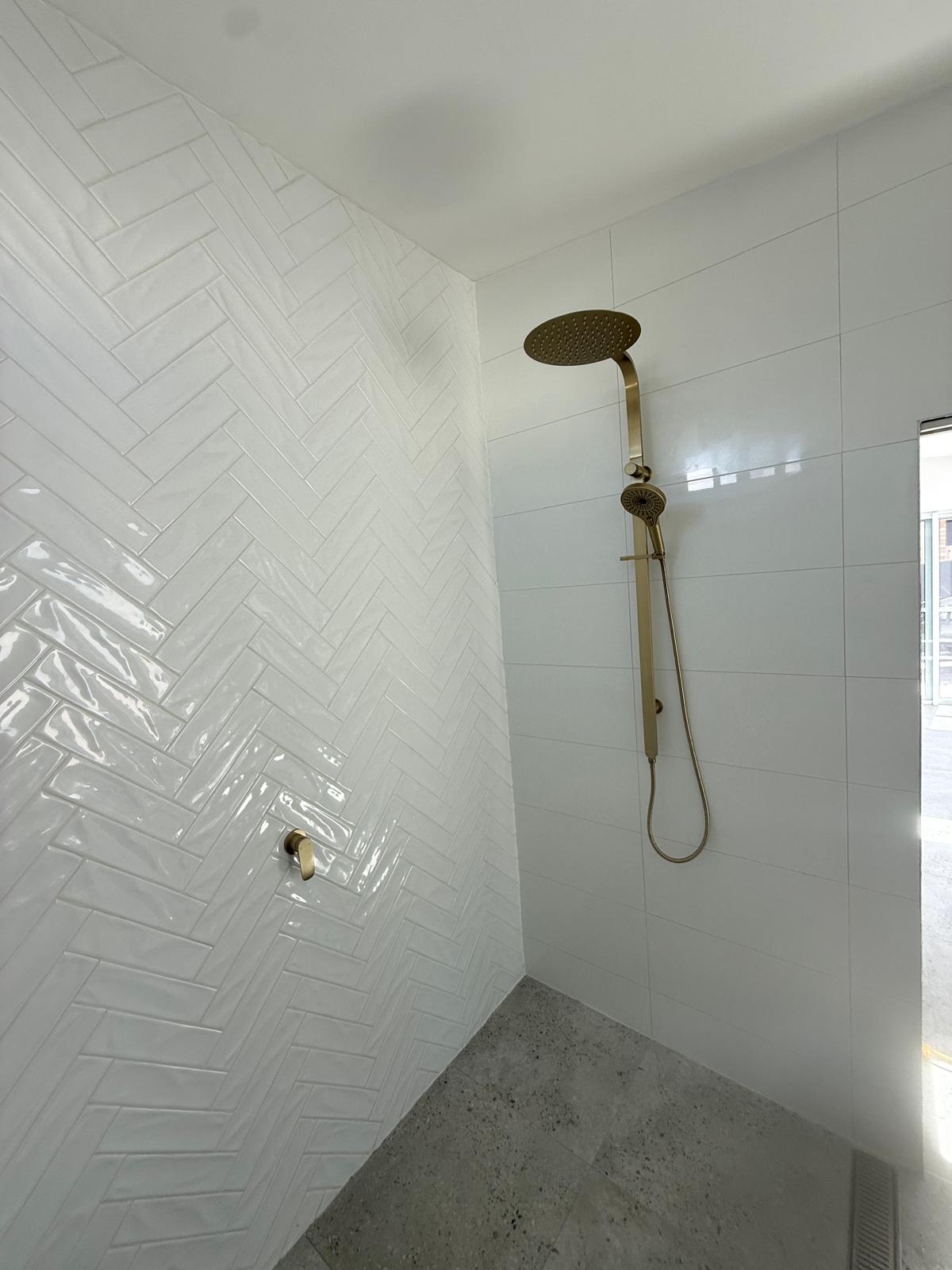 Walk-in shower — herringbone tile & brass — plumbing work completed in Kiama by Shellharbour Plumbing (licensed Illawarra plumber)