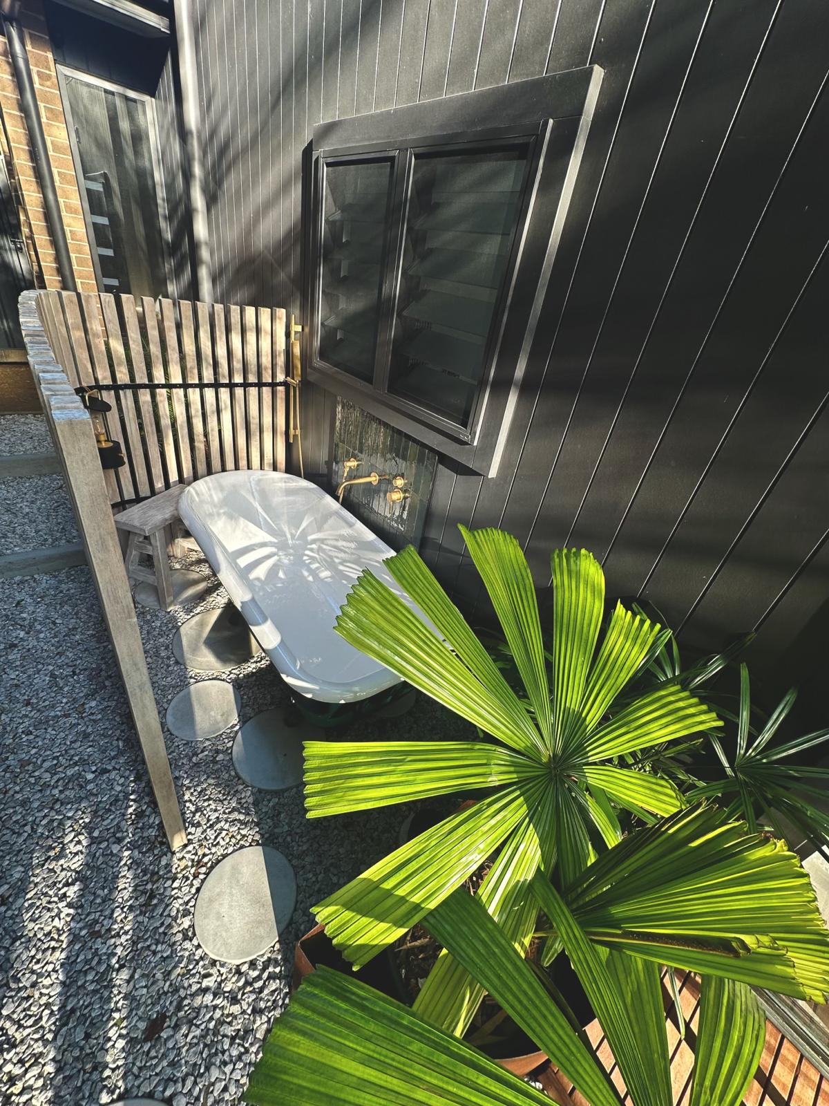 Outdoor bath — black cladding & brass — plumbing work completed in Gerringong by Shellharbour Plumbing (licensed Illawarra plumber)
